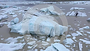 Flying over floating icebergs in Fjallsarlon glacial lagoon, Iceland. Aerial view of melting ice cap as result of global warming