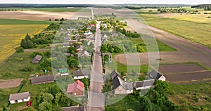 flying over a gravel road in a village with sheds and garden plots