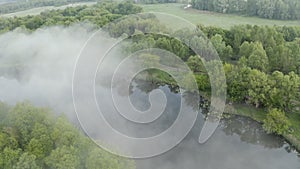 Flying over a green misty forest near the fog river