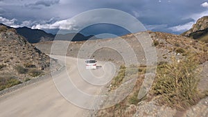 Flying over ground road driving van car between mountains in desert