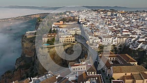 Flying over houses and Puente Nuevo bridge in Ronda, Andalusia. Great aerial morning view of Ronda, Spain with fog