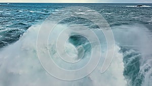 Flying over huge wave in atlantic ocean. Aerial filming breaking surf with foam. Powerful stormy sea or ocean waves