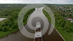 Flying over a large cargo ship with open holds sailing down a calm river