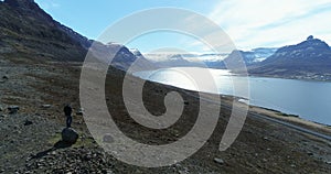 Flying over man looking out over beautiful fjord in Iceland