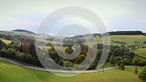 Flying over mountain valley with narrow winding car road. Countryside landscape