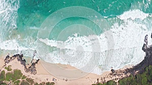 Flying over the ocean at the golden hour. Giant waves foaming and splashing in the ocean. Surfers ride the waves. The