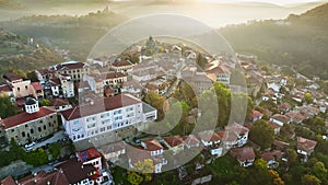 Flying over old houses, Ascension Cathedral and river in the canyon in Veliko Tarnovo. Aerial shot of sunny slightly