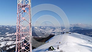 Flying over radio communications tower, mountain snow covered winter landscape.