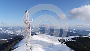 Flying over radio communications tower, mountain snow covered winter landscape.