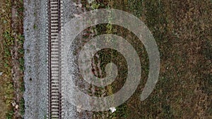 Flying over a railroad track on an embankment in a field of wild flowers. Infrastructure element