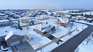 Flying over snow covered residential houses and yards along suburban street