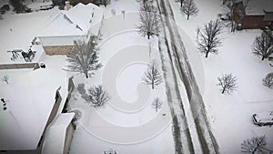 Flying over snow covered residential houses and yards along suburban street