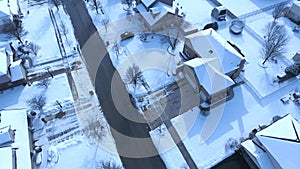 Flying over snow covered residential houses and yards along suburban street