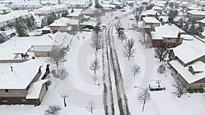 Flying over snow covered residential houses and yards along suburban street