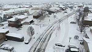 Flying over snow covered residential houses and yards along suburban street