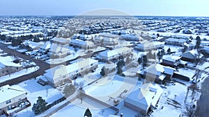 Flying over snow covered residential houses and yards along suburban street