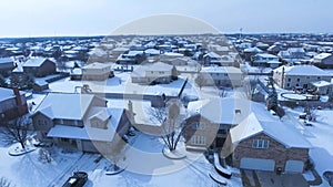 Flying over snow covered residential houses and yards along suburban street