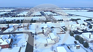 Flying over snow covered residential houses and yards along suburban street