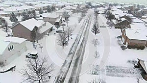 Flying over snow covered residential houses and yards along suburban street