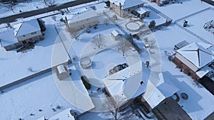 Flying over snow covered residential houses and yards along suburban street