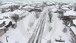 Flying over snow covered residential houses and yards along suburban street