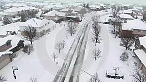 Flying over snow covered residential houses and yards along suburban street