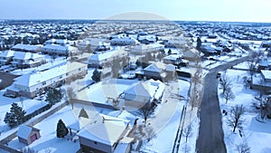 Flying over snow covered residential houses and yards along suburban street