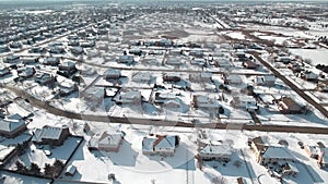 Flying over snow covered residential houses and yards along suburban street