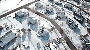 Flying over snow covered residential houses and yards along suburban street