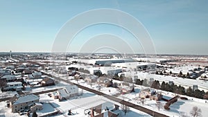 Flying over snow covered residential houses and yards along suburban street