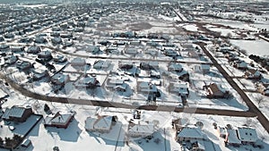 Flying over snow covered residential houses and yards along suburban street