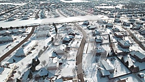 Flying over snow covered residential houses and yards along suburban street