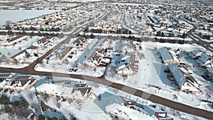 Flying over snow covered residential houses and yards along suburban street