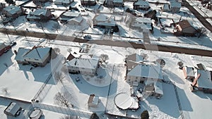 Flying over snow covered residential houses and yards along suburban street