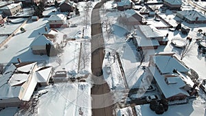 Flying over snow covered residential houses and yards along suburban street