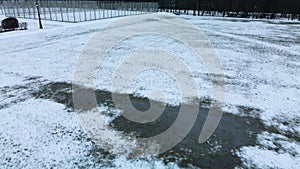 Flying over a sports field in a snow-covered city park. Aerial photography.