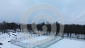 Flying over a sports field in a snow-covered city park. Aerial photography.