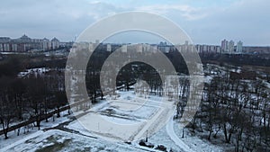 Flying over a sports field in a snow-covered city park. Aerial photography.