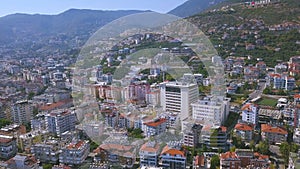 Flying over sunny town Alanya in Turkey located by the Mediterranean sea. Art. Aerial view of the mountain slope covered