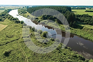 Flying over the village, fields, river and forests. Beautiful bird`s-eye view on hanging old bridge over the river.