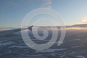 Flying over white snowy landscape with many forests in Finland orange sunset landscape