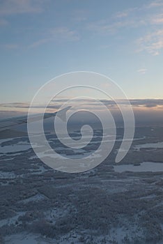 Flying over white snowy landscape with many forests in Finland sunset landscape