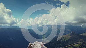 Flying over woman with raised hands standing on Piz Boe mountain top in Dolomites