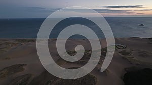 Flying parallel to coast over deserted sand dunes on beach before sunrise