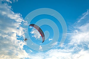 A flying paramotor on a vibrant sky with cloud.