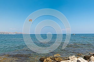 Flying paratrooper with full color parachute, isolated on a blue sky near Rhodes island, Greece