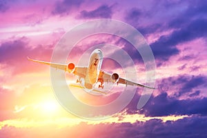 Flying passenger airplane against the background of evening clouds backlit by the sun. The concept of tourism, vacation, travel