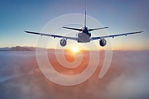 Flying of the passenger plane above the clouds and mountains