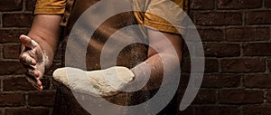 Flying pizza dough with flour scattering in a freeze motion of a cloud of flour midair on black. Cook hands kneading dough. copy