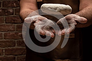 Flying pizza dough with flour scattering in a freeze motion of a cloud of flour midair on black. Cook hands kneading dough. copy